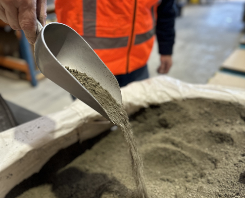A scoop of the sign bag filler material being dropped from a metal scoop